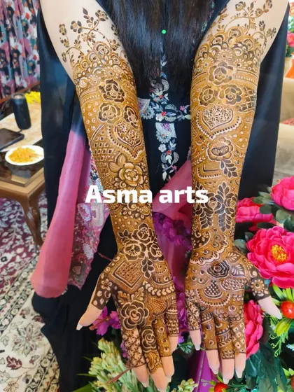 This design features beautiful heart shapes and the couple's initials hidden within the floral patterns on the forearms. It's a sweet and personal touch within a classic bridal design.