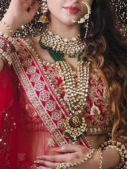 A close-up of a bride wearing a heavy, layered Kundan set with red and white stones. The intricate details of the hathphool are also visible.