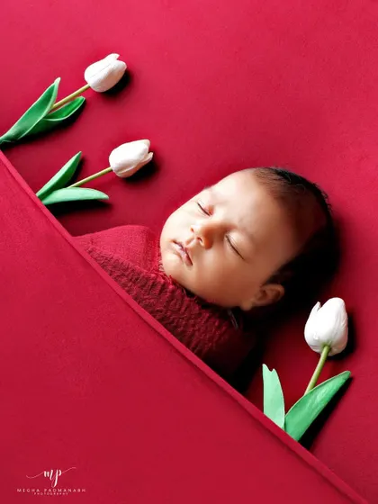 A close-up of the baby's face in the red tulip setup.