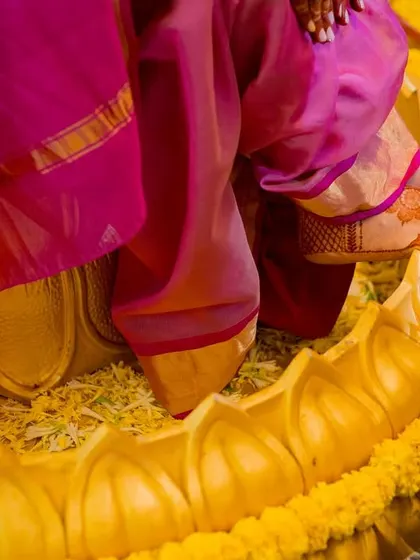 A detail shot focusing on the bride's feet, adorned with mehndi, as she stands in a decorative urn during her haldi ceremony.