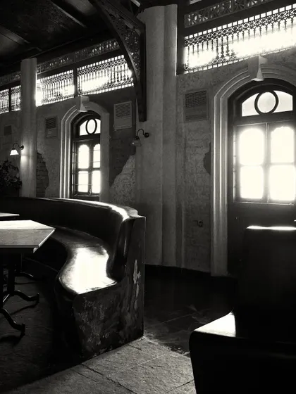 Sunlight streams through the large windows, highlighting the texture of the stone floor and the custom-built, wave-like bench.