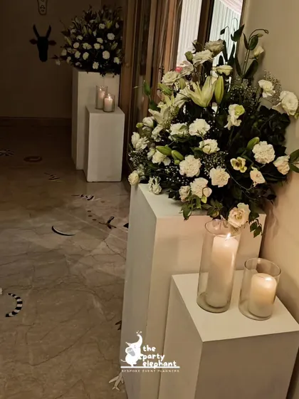 I used modern white pedestals of varying heights to display large bouquets of white lilies and carnations, adding a touch of contemporary style to the classic floral arrangements.