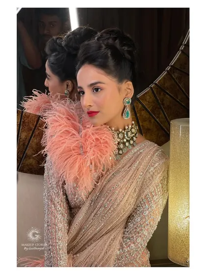 Krishna's stunning cocktail look, featuring a dramatic high bun and a bold lip. The makeup is pure Hollywood glamour, designed to make a statement at any evening event.
