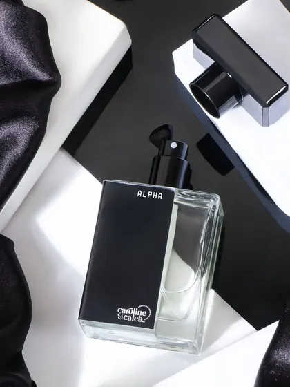 A high contrast, black and white themed shot for 'Alpha' perfume. The geometric shapes and silky fabric create a visually interesting composition that feels modern and bold.