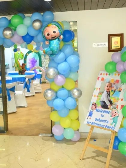 The entrance to a Cocomelon-themed first birthday party, with a welcome sign and a colorful balloon arch.
