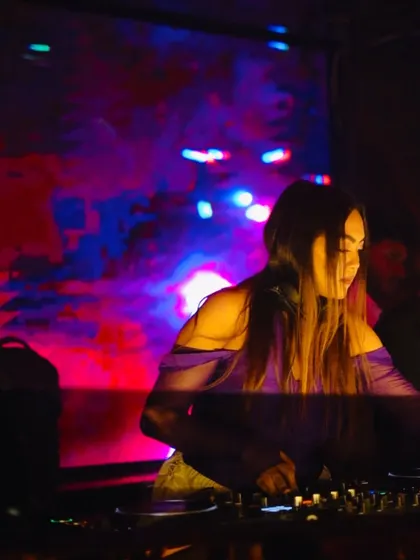 Mixing under colorful lights, completely absorbed in the music.