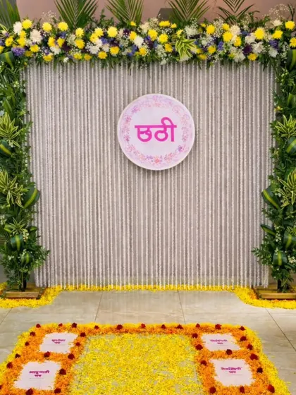 I design decorations for traditional ceremonies like this Chhathi Pooja, focusing on elegance and cultural significance. This setup features a backdrop of white flower strings, a frame of fresh greenery, and a beautiful marigold rangoli on the floor.