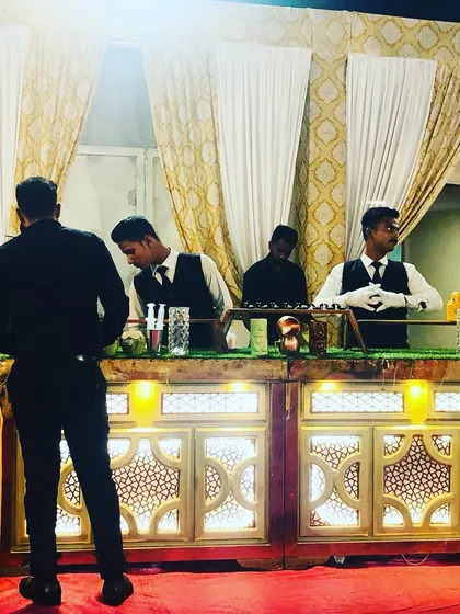 Our professional staff ready to serve guests at the beverage counter during an engagement party. The counter design is consistent with the overall gold and white theme of the event.