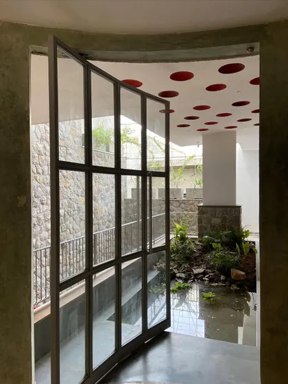 The large pivot door in its open position, creating a seamless transition between the interior space and the biophilic water feature.