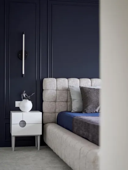 A glimpse into the guest bedroom, where the deep blue walls create a sense of calm and intimacy. The tufted headboard adds a layer of texture and comfort to the space.