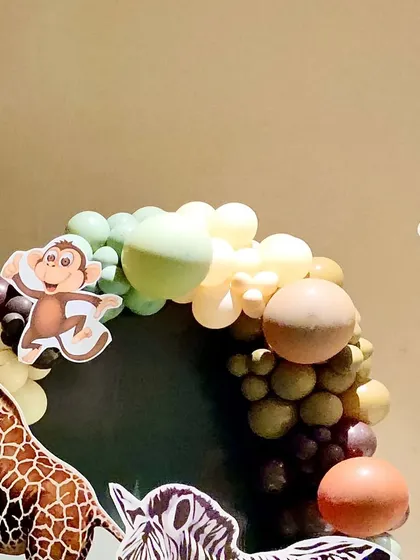 A close-up of the balloon arch with a giraffe cutout, showing the earthy color palette of the jungle theme.