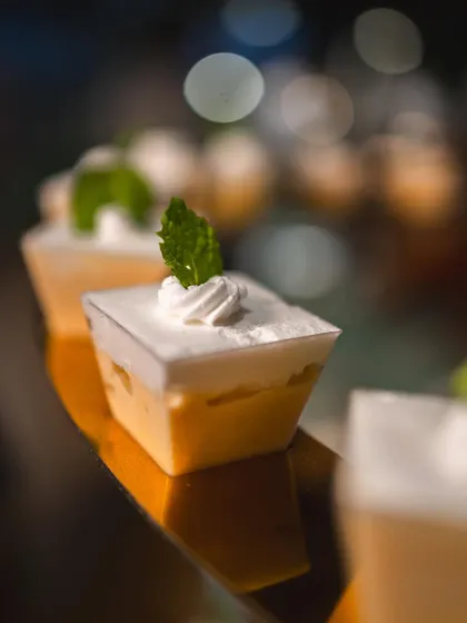 A close-up of delicate dessert cups with a light mousse and mint garnish.