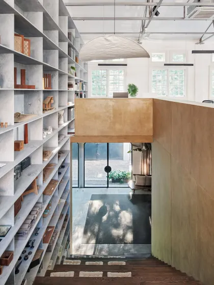 The double-volume space in our studio features a floor-to-ceiling grid of marble shelves. This element is both functional for storage and instrumental in breaking down the scale of the large space.