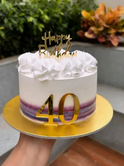 Another take on a 40th birthday cake, this one features a watercolor stripe effect in purple hues and delicate white ruffles on top.