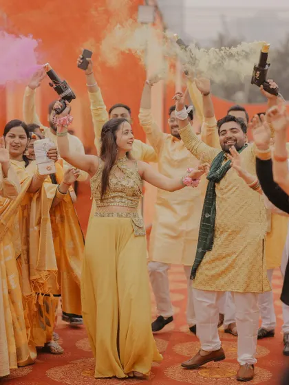 The whole wedding party joins in the celebration, dancing and using color smoke guns to create a festive and energetic atmosphere at the Haldi.