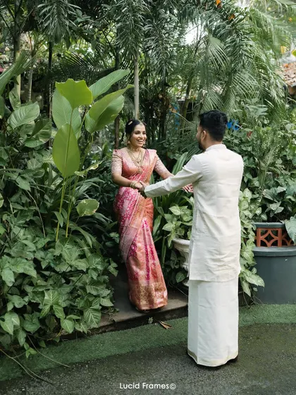 The groom leads his bride through a lush garden path, a romantic "first look" moment.