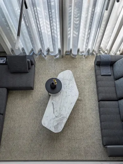 An overhead view of the living room, highlighting the geometric arrangement of the sectional sofa and the organic shape of the marble coffee table. This composition creates a balanced and inviting social space.
