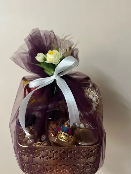 A single Diwali hamper wrapped in deep purple net with a white ribbon. The elegant packing makes it a beautiful gift for friends, family, or colleagues.