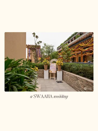 A wide view of a vibrant outdoor pre-wedding event, with a welcome sign and colorful floral arrangements leading the way.