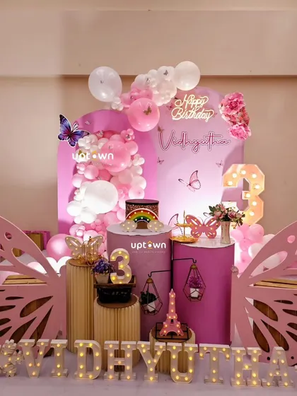 A pink and purple butterfly theme for a 3rd birthday, with large wing props creating a photo-op spot.