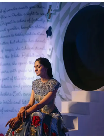 The bride takes a quiet moment, seated by the storybook backdrop. The dramatic lighting and unique setting create a truly memorable portrait.