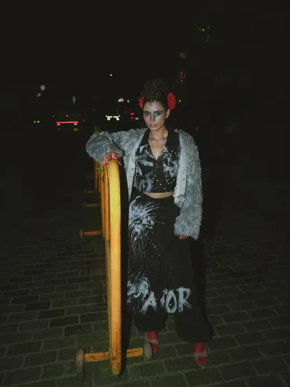 A night scene from the 'Lampione' editorial. The styling combines a fuzzy grey jacket with custom-painted trousers, using the urban environment and flash photography to create a raw, edgy look.