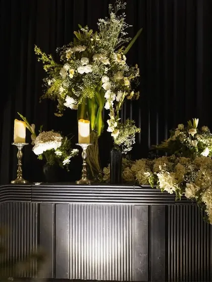 The magic is in the details. A modern, fluted console table is adorned with a cascading arrangement of white hydrangeas and elegant candles.