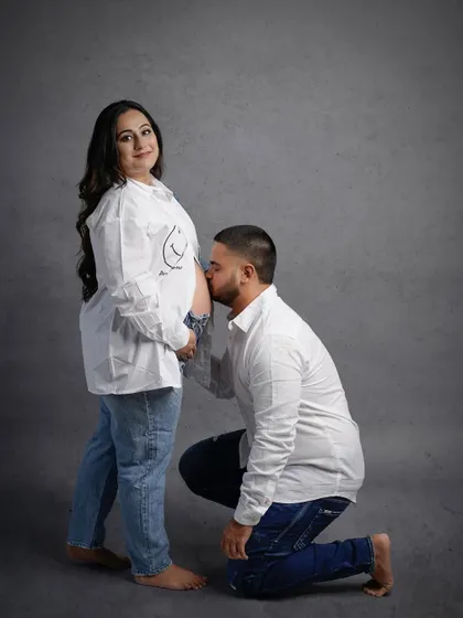 A classic maternity pose with the partner kissing the baby bump, all while keeping the vibe casual and sweet.