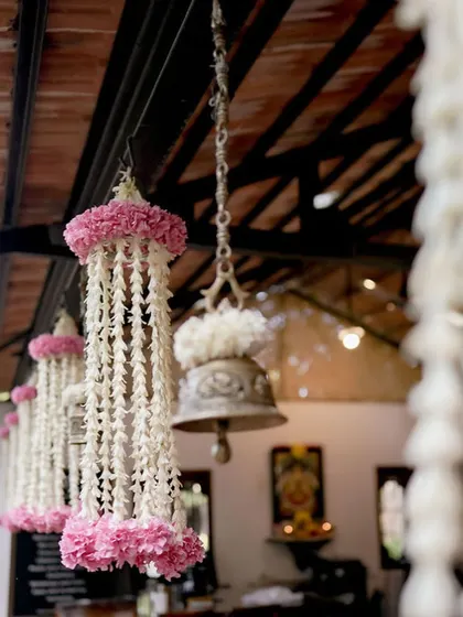 Hanging floral decor with pink flowers and traditional bells.