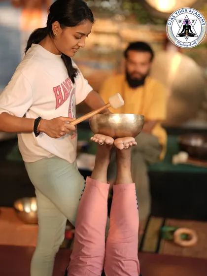 A student practices foot reflexology with a singing bowl on her partner. This hands-on learning helps you understand the technique's power to ground energy and promote deep relaxation.