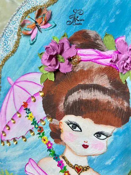 A detail shot focusing on the top part of the "girl with umbrella" artwork, showing the sculpted butterfly and the flowers adorning her hair.