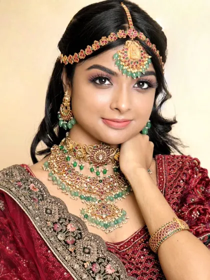A classic portrait of a model wearing our green Kundan reception set. The hand-on-chin pose highlights the matching bracelet.