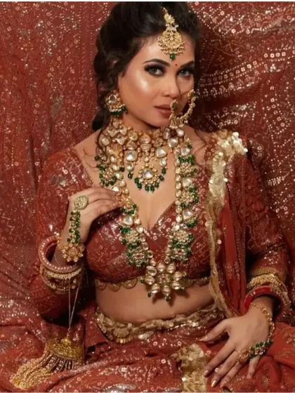 Here is another example of a layered bridal set with green beads, featuring a choker, a long necklace with a large pendant, and matching haath phool and maang tikka.
