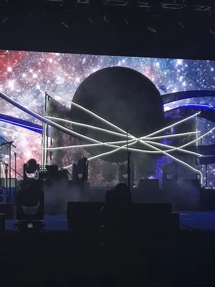 The main stage for the celestial sangeet, featuring a massive LED screen displaying a galaxy graphic. The lighting and stage design work together to create a fully immersive thematic experience.