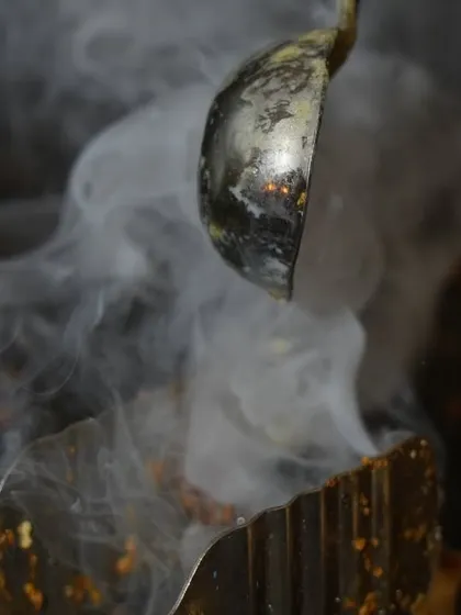 The sizzle and smoke from a hot tadka (tempering) being added to a dish. This action shot captures the authentic sounds and smells of live Indian cooking.
