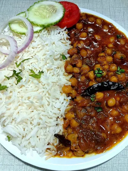 A plate of my classic Chole Chawal, a favorite for any community feast. I serve it with fluffy basmati rice and a fresh salad, making it a complete and satisfying meal for your guests.