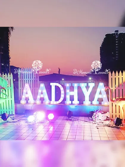 An outdoor photo opportunity with large, illuminated marquee letters and flamingo props set against the evening sky.