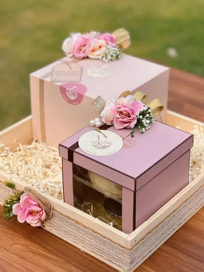 Bespoke return favours designed to share sweetness. These gift boxes, presented in a rustic wooden tray, feature our signature pink packaging, floral toppers, and custom tags, creating a warm and inviting thank you gift for guests.