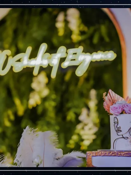 A detail shot of the artistic cake, featuring a line-drawn face and delicate pink roses, with the event's neon sign glowing in the background.