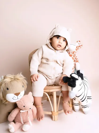 This handsome little boy is surrounded by his safari animal friends. The neutral-toned outfit and stuffed animals create a sweet and simple themed portrait.