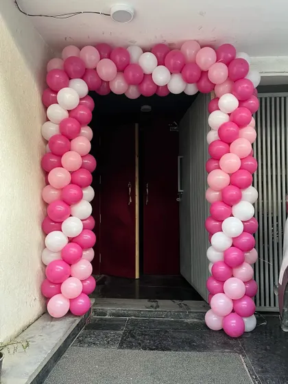 The entrance to the party, decorated with a pink and white balloon arch to welcome guests.