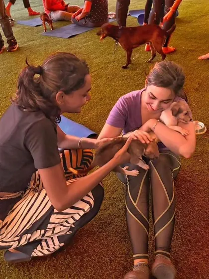 Two participants share a moment of joy, cuddling with tiny, adorable puppies during a break in their yoga class.
