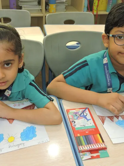 Two students collaborate on their drawings, sharing ideas and crayons during a creative classroom session.