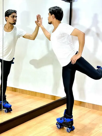 Using the studio mirror to check alignment while balancing on one leg in roller skates.