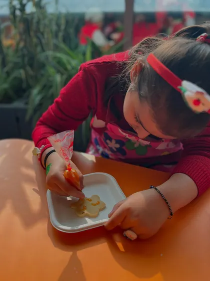 A young girl concentrates on piping icing onto a cookie, a fun activity that also develops fine motor control.