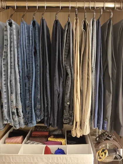 For men, an organized wardrobe means efficiency. Here, trousers are hung on sturdy hangers, while belts and other accessories are neatly stored in compartmentalized bins below, creating a system that saves time.