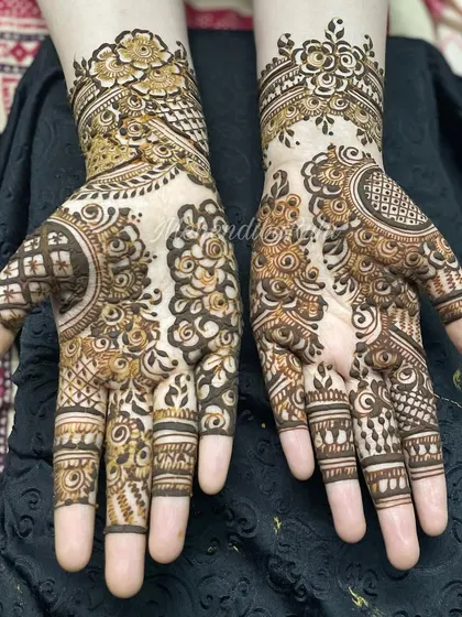 A classic Eid henna design from 2023. It features beautiful floral work on the back of the hand and intricate details on the fingers.