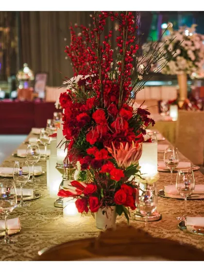 A stunning tablescape dominated by a dramatic red floral centerpiece, showcasing our ability to coordinate with decor to create a cohesive and visually impactful theme.