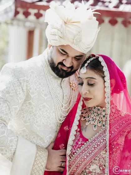 An intimate portrait of the couple on their wedding day, showcasing the bride's stunning pink lehenga and the groom's elegant sherwani.