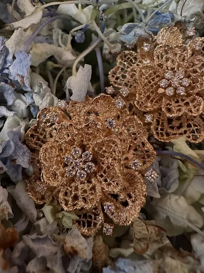 A product shot of the gold rose tops worn by Khushi Kapoor. These earrings are handcrafted with layers of woven 18k gold to resemble blooming roses, with diamond clusters at the center.